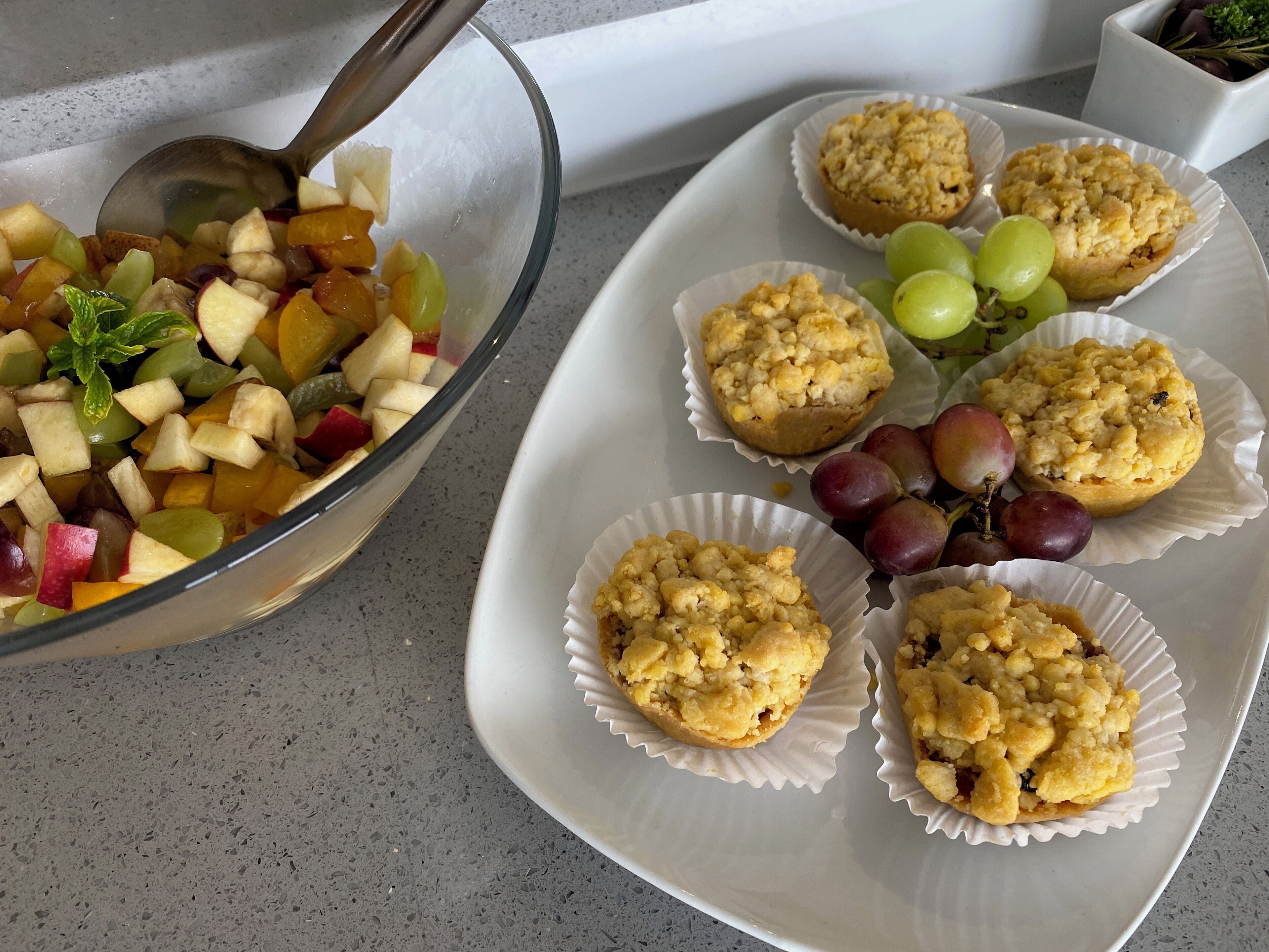 Una ensalada de frutas y muffins en una bandeja.