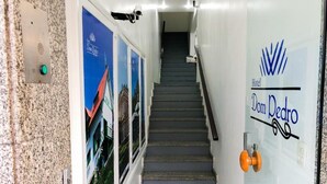Un couloir d’hôtel avec un escalier, un interphone fixé au mur et une affiche publicitaire pour l’hôtel.