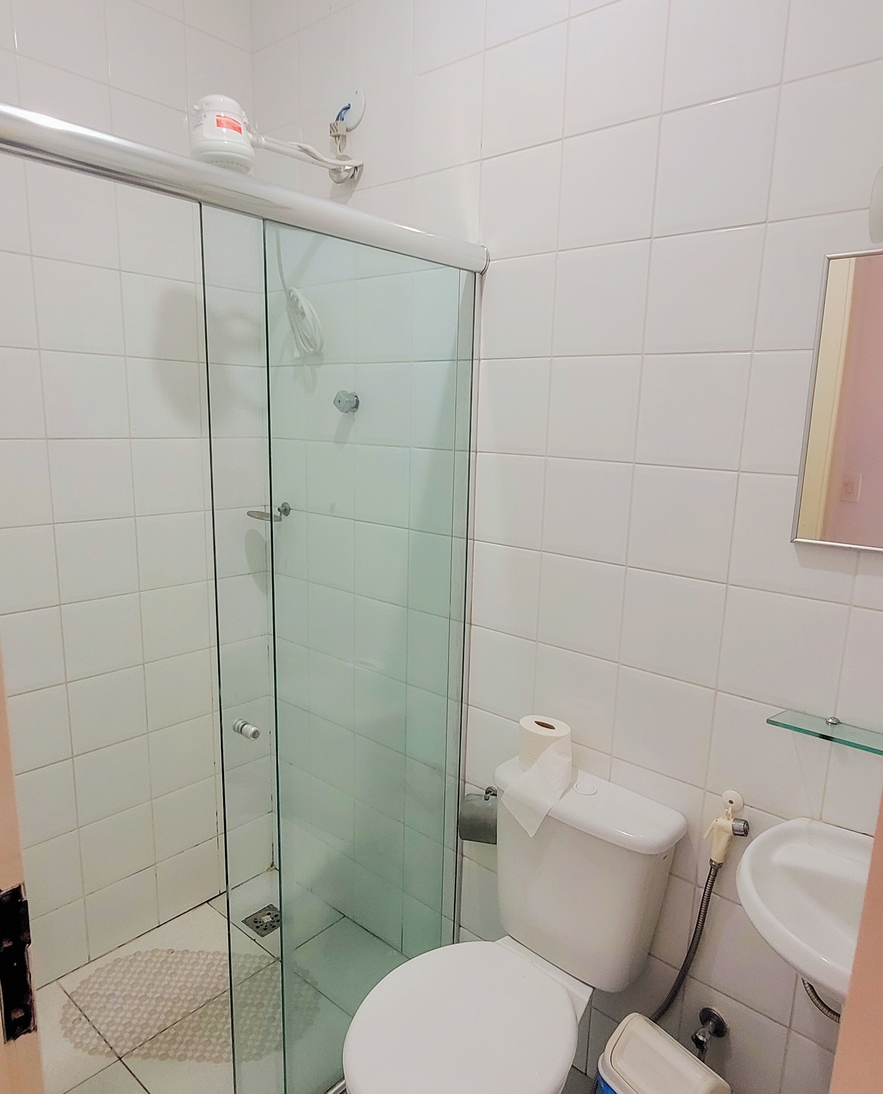 Un baño con cabina de ducha de vidrio, inodoro y lavabo.