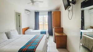 Une chambre d’hôtel avec deux lits, un ventilateur de plafond, un téléviseur à écran plat et une grande fenêtre avec des rideaux.