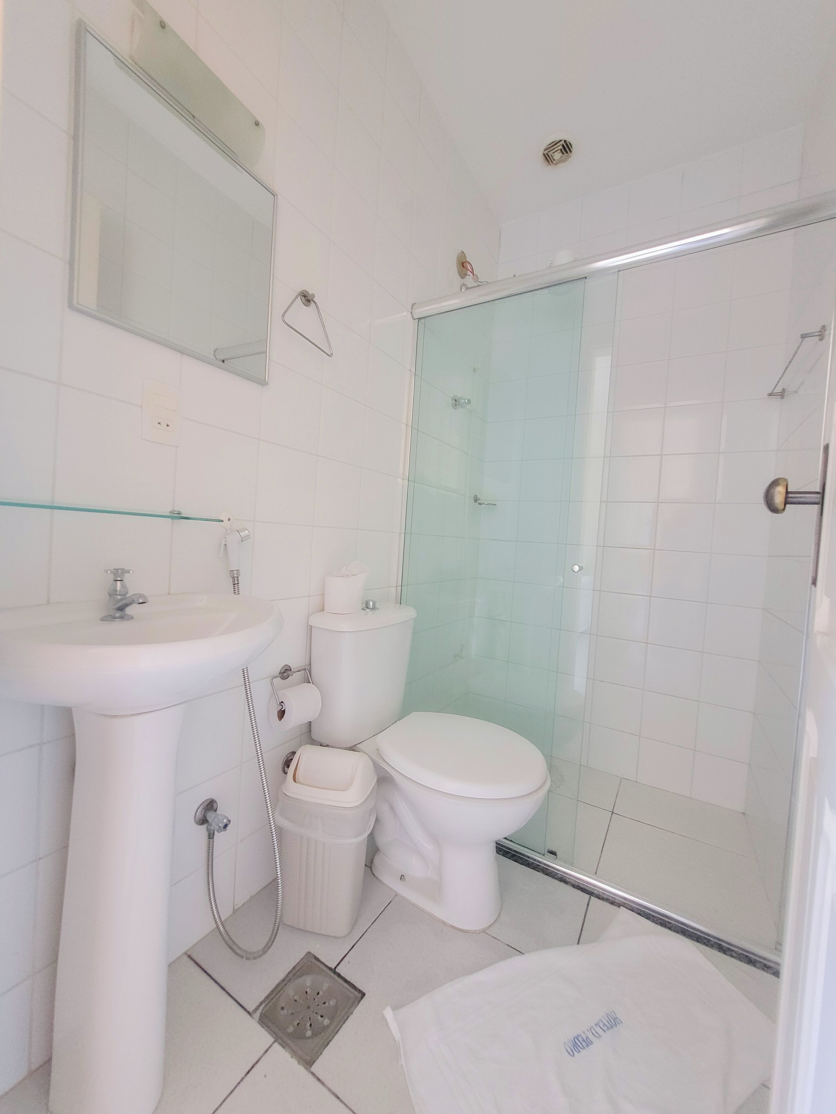 Un baño con lavamanos, inodoro y cabina de ducha con mampara de vidrio.