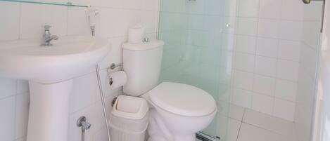 Un baño con lavamanos, inodoro y cabina de ducha con mampara de vidrio.