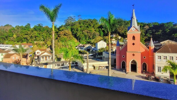 Une vue d’une ville avec une église rose imposante, des palmiers et un ciel bleu dégagé.