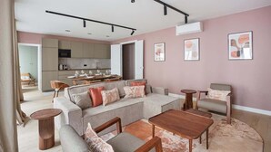 A modern living room with a sectional sofa, a coffee table, and a dining area with a kitchen in the background. - Magnificent New Apartment  Beaubourg/Le Marais (Paris)