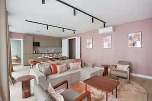 Una sala de estar moderna con un sofá modular, una mesa de centro y un comedor, con una cocina al fondo.