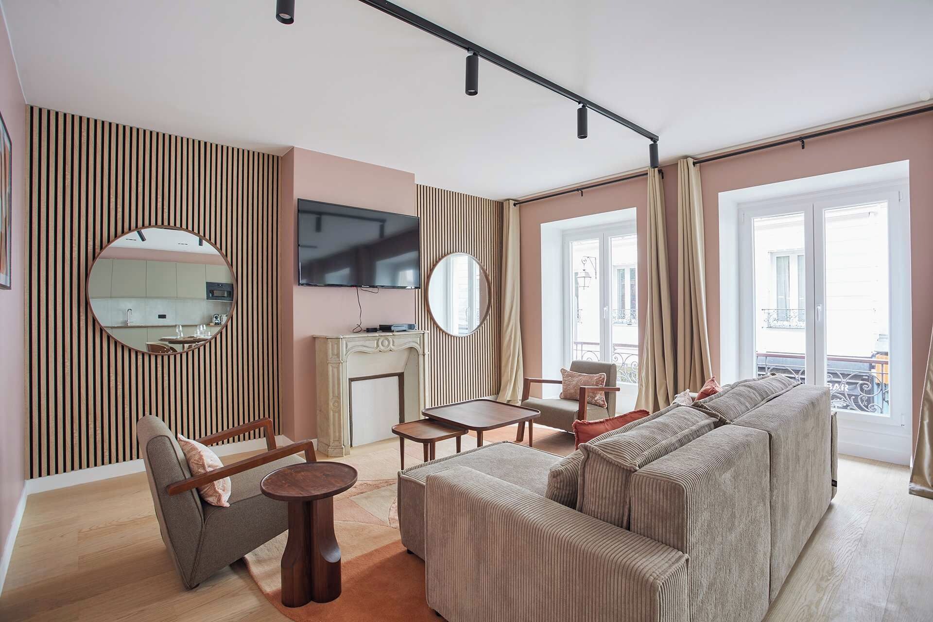 A modern living room with a sofa, armchairs, a coffee table, and a TV mounted on the wall.