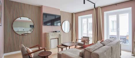 A modern living room with a sofa, armchairs, a coffee table, and a TV mounted on the wall.