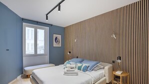 A modern bedroom with a bed, bedside tables, a window, and a wall with vertical wooden slats. - Magnificent New Apartment  Beaubourg/Le Marais (Paris)