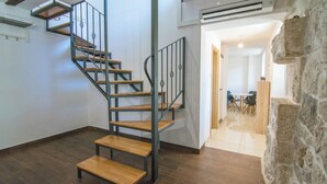 Una escalera de caracol con escalones de madera y barandillas de metal, que conduce a un piso superior.