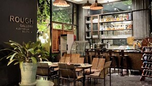 Un interior de cafetería con mesas, sillas y una barra.