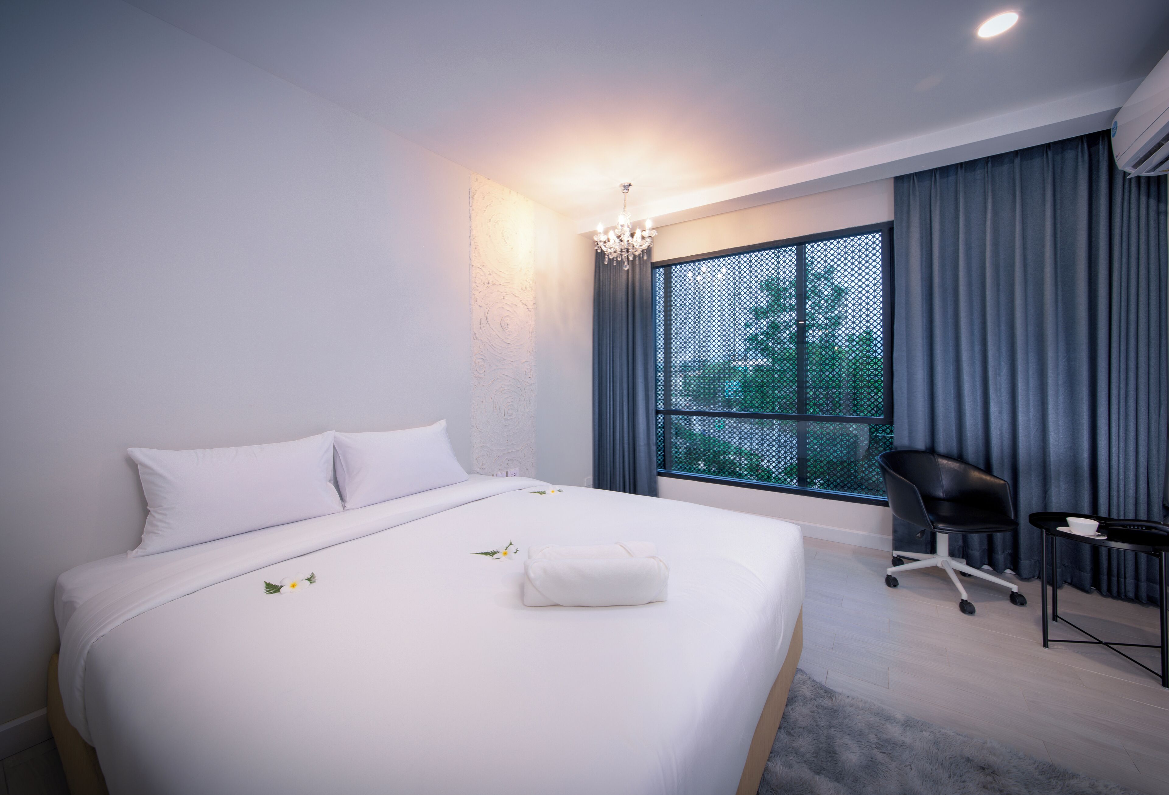 A modern hotel room with a large bed, a desk, and a chair.