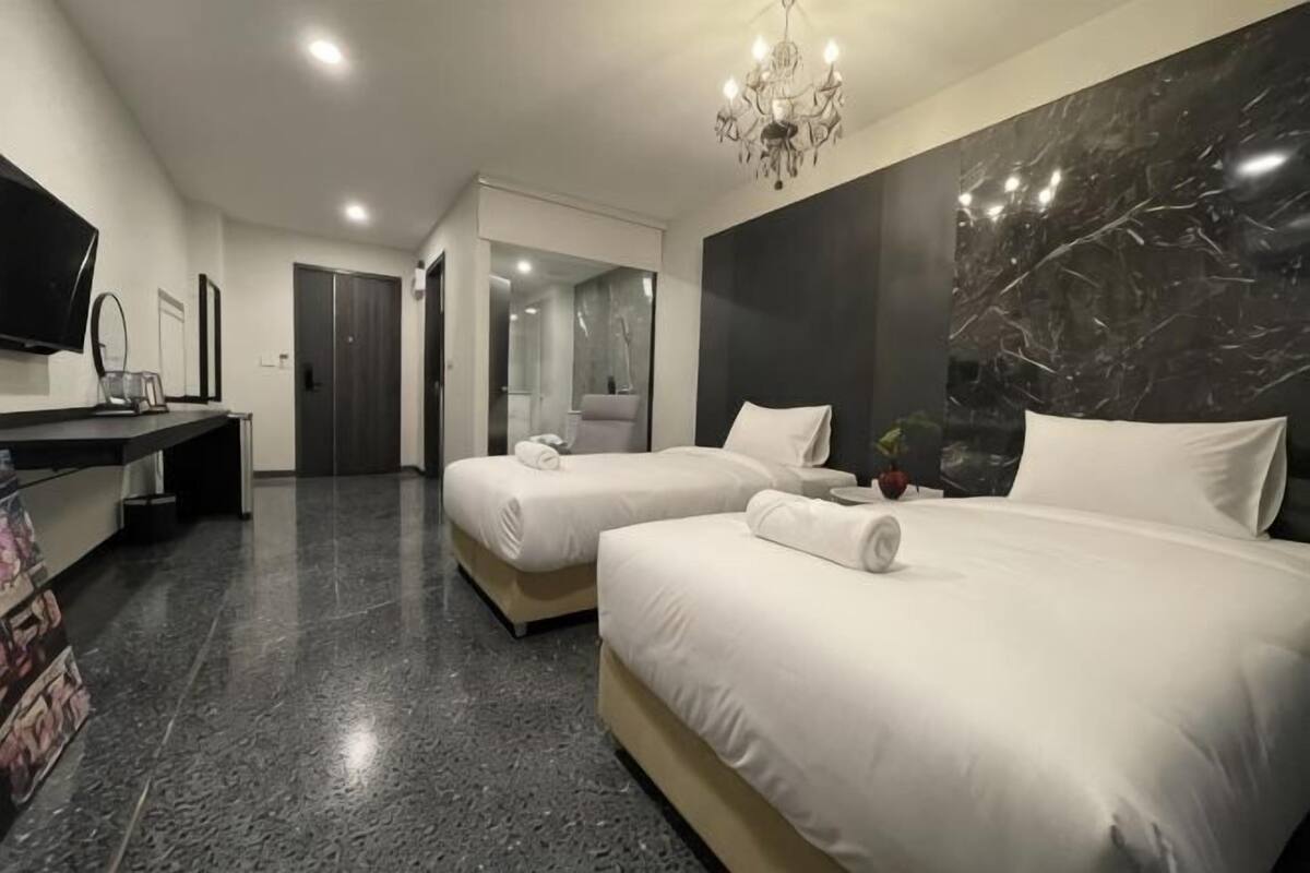 A hotel room with two beds, a TV, a desk, and a mirror.