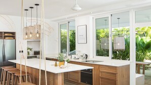 Una cocina moderna con una isla grande, taburetes de madera y una lámpara colgante.