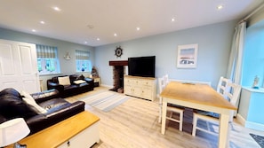 A living room with a sofa, a coffee table, a TV, a fireplace, and a dining table with chairs.