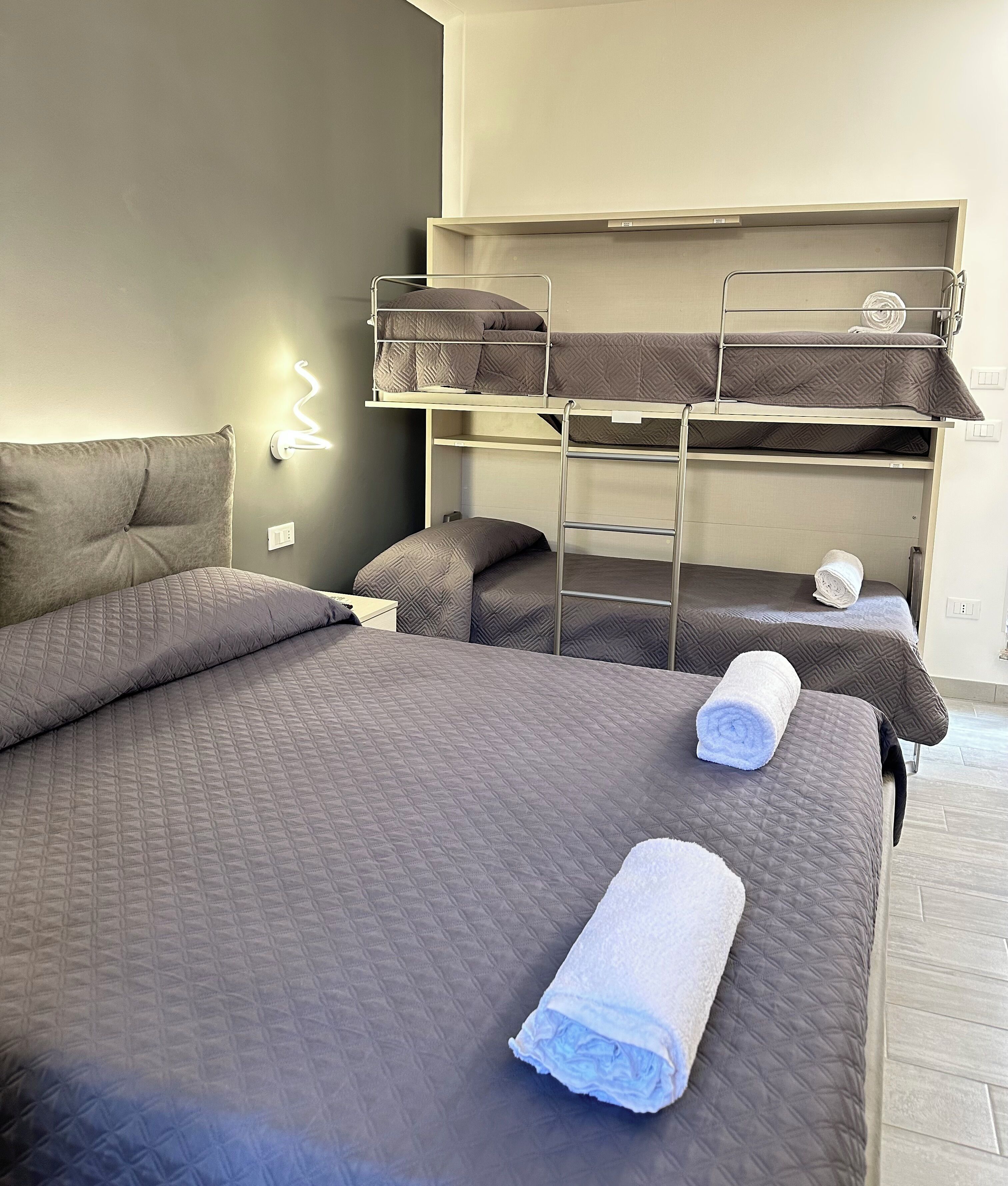 Habitación de hotel con una cama grande, una litera y una lámpara fijada a la pared.