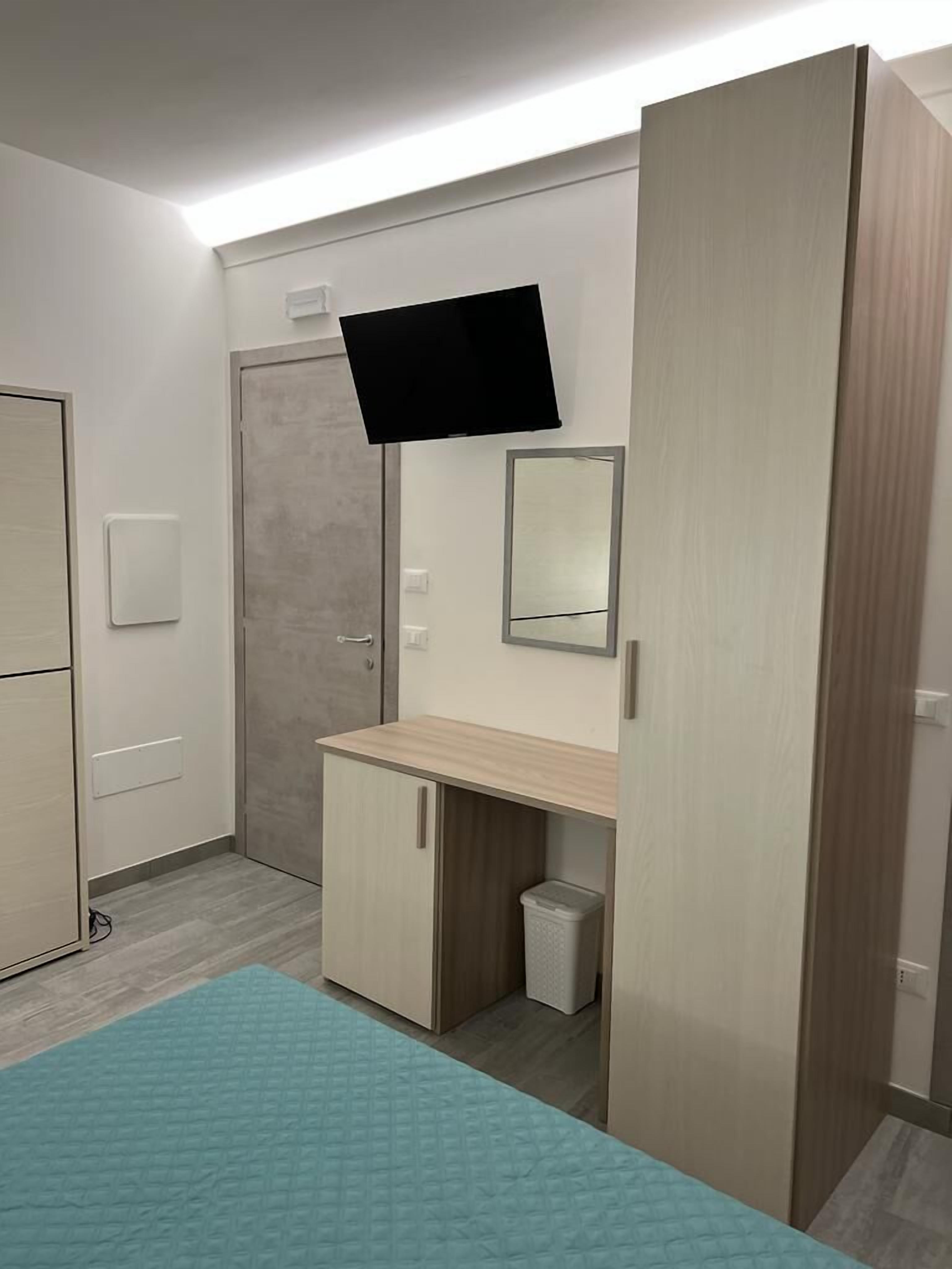 Un dormitorio con cama, armario, espejo y televisor.