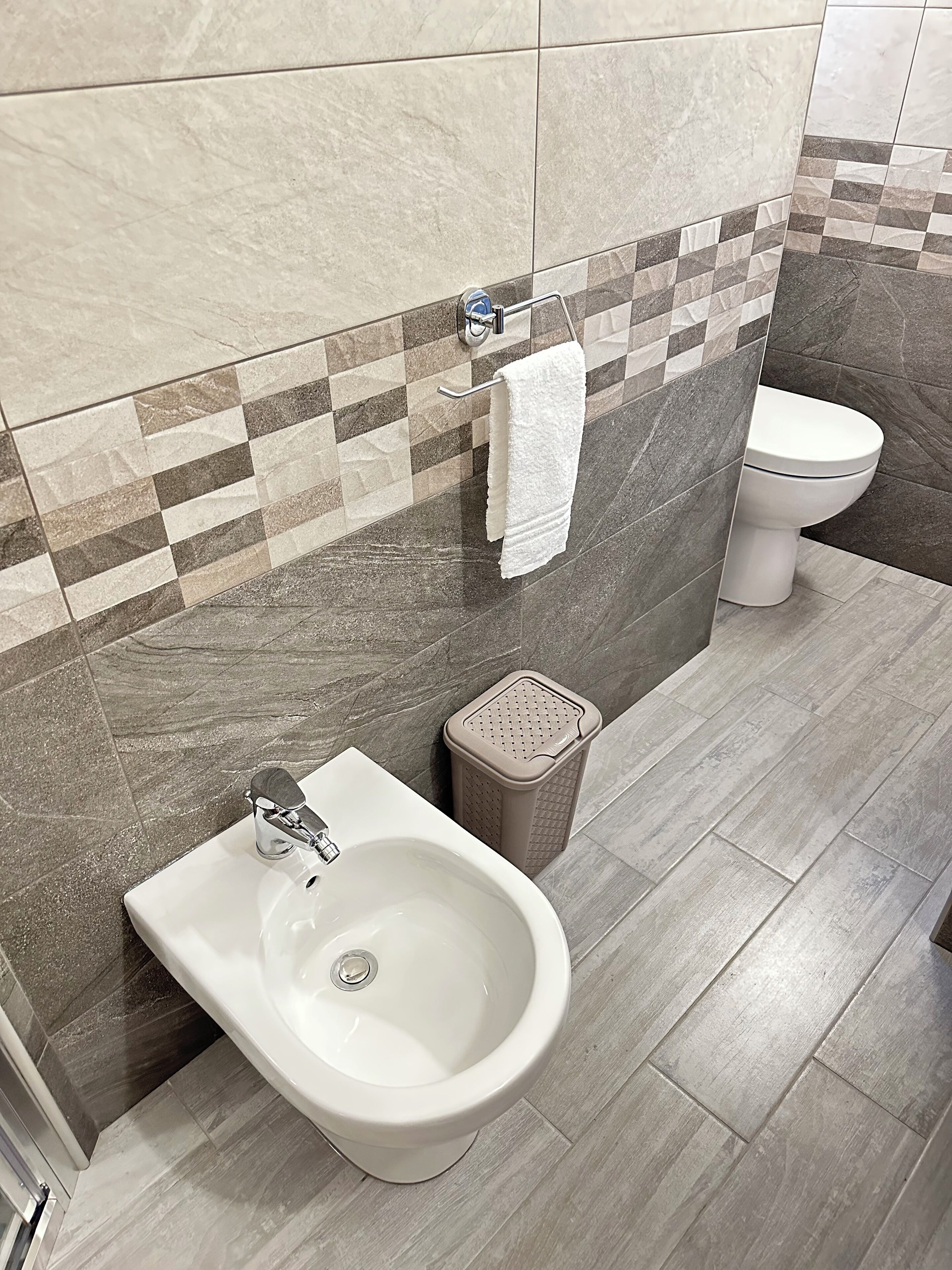 Un baño con bidé, inodoro y un cesto de basura.