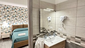 Een moderne badkamer met een houten wastafelmeubel, een grote spiegel en een haardroger bevestigd aan de muur.