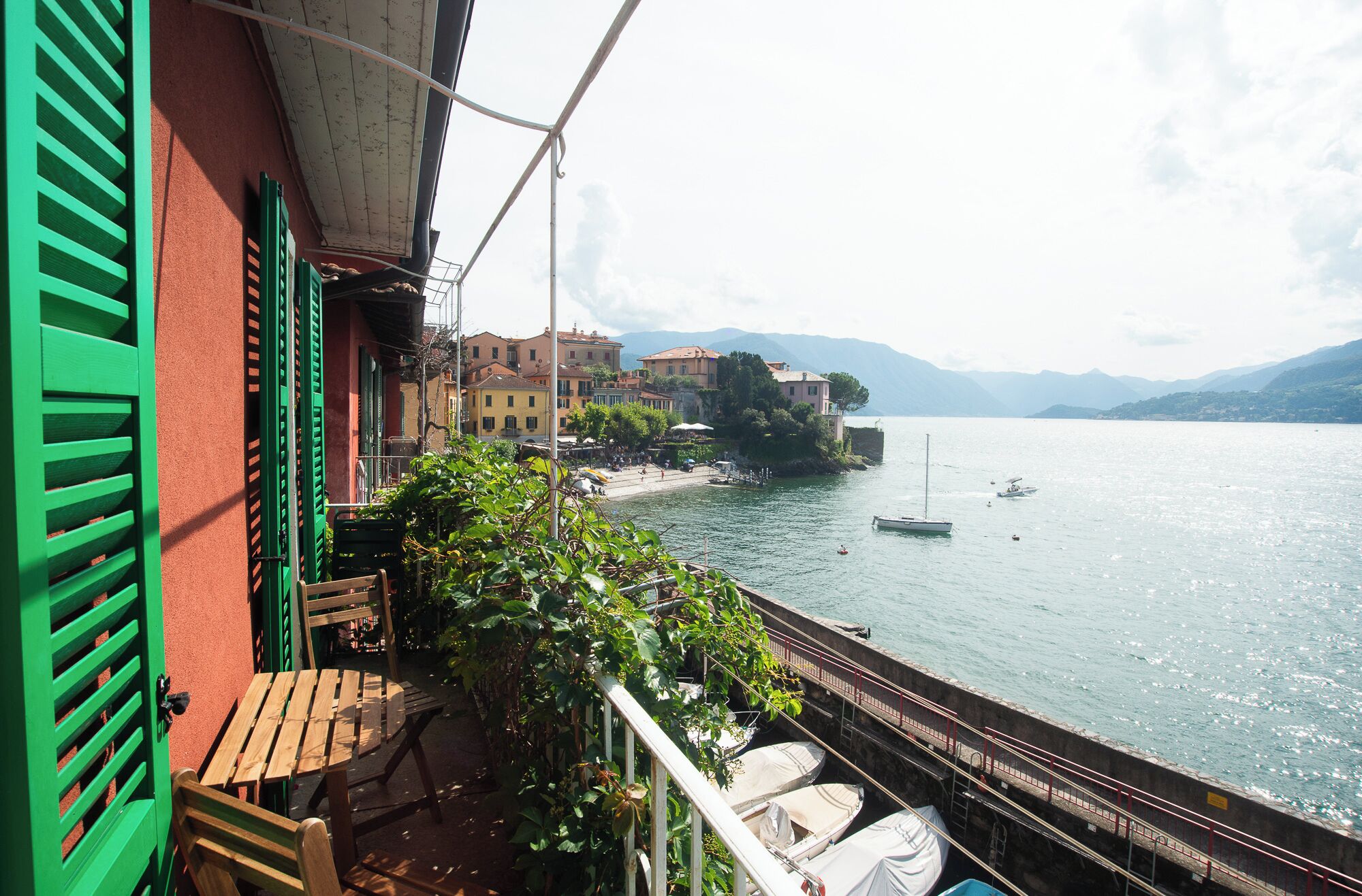 Un balcón con vista a un lago, barcos y edificios al fondo.