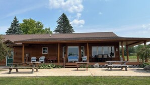 Een blokhut met een veranda, buitenzitplaatsen en een picknicktafel.