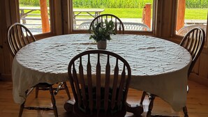 Een houten interieur met een ronde tafel, stoelen en een hanglamp.