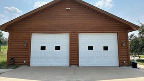 Een garage voor twee auto's met een zadeldak en houten bekleding.