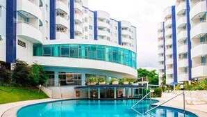 Ein modernes Hotel mit Pool, mehreren Balkonen und einer geschwungenen Glasfassade.