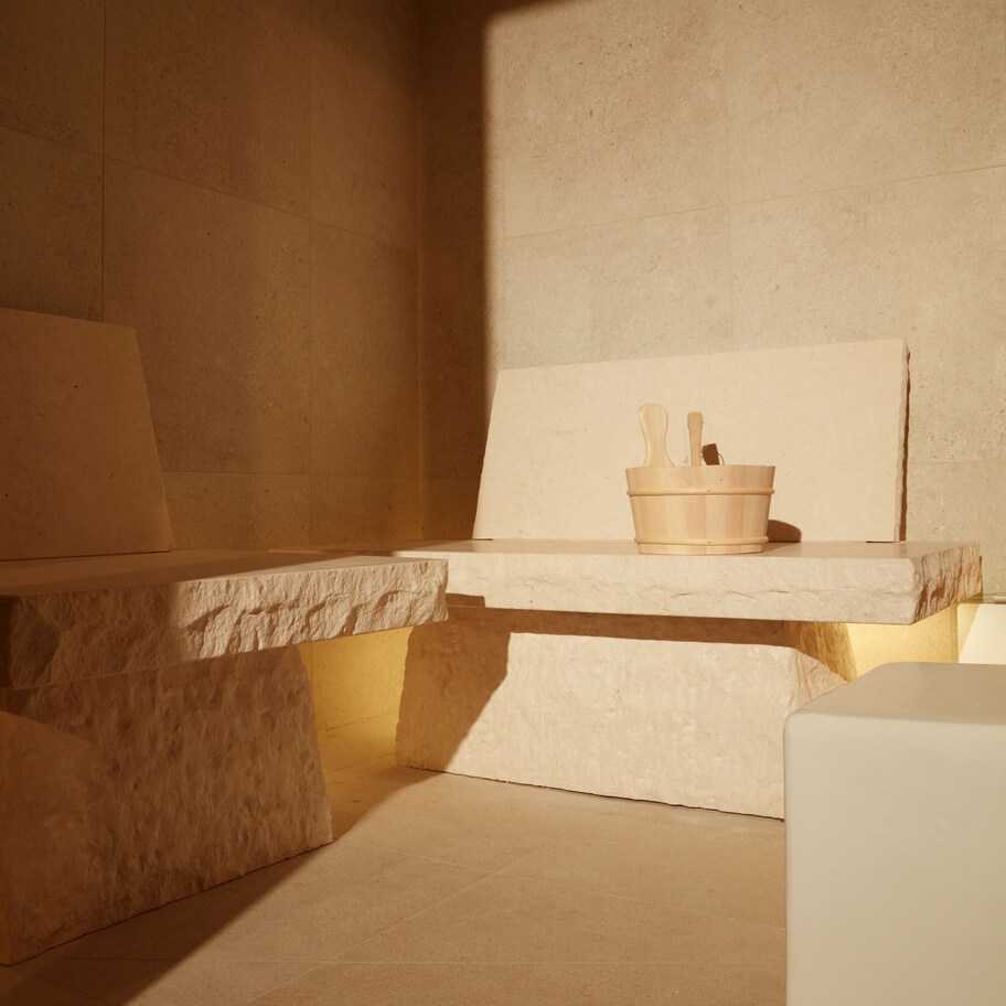 A minimalist bathroom with a bathtub, a wooden bucket, and a shelf.