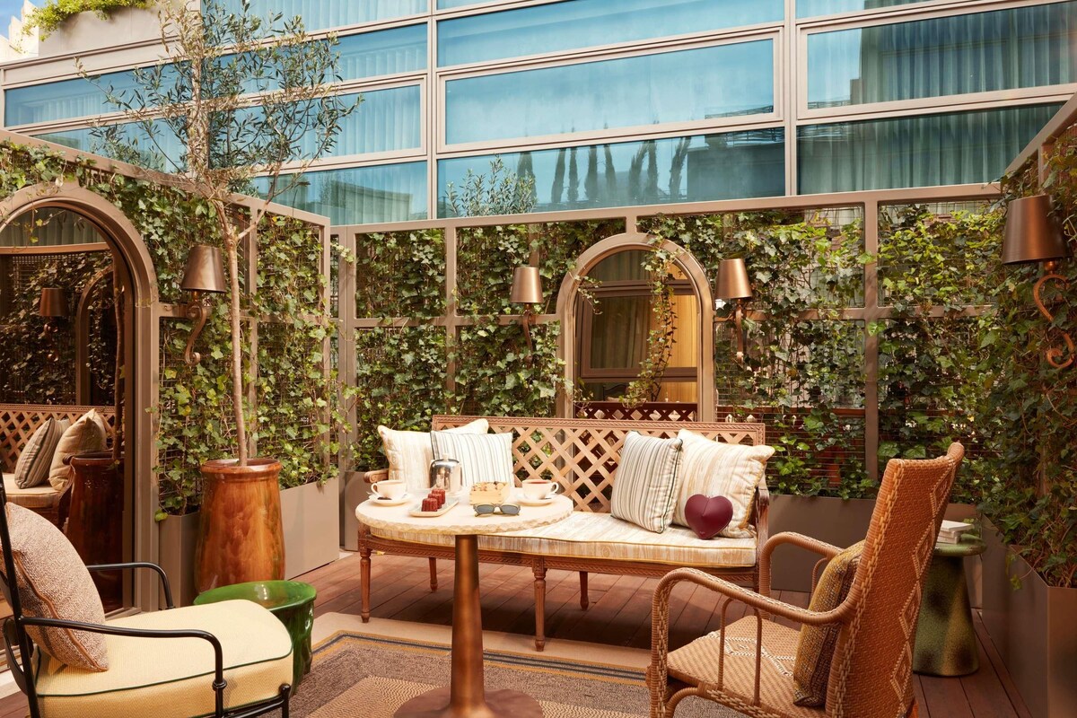 A cozy outdoor seating area with a round table, cushioned chairs, and a bench.