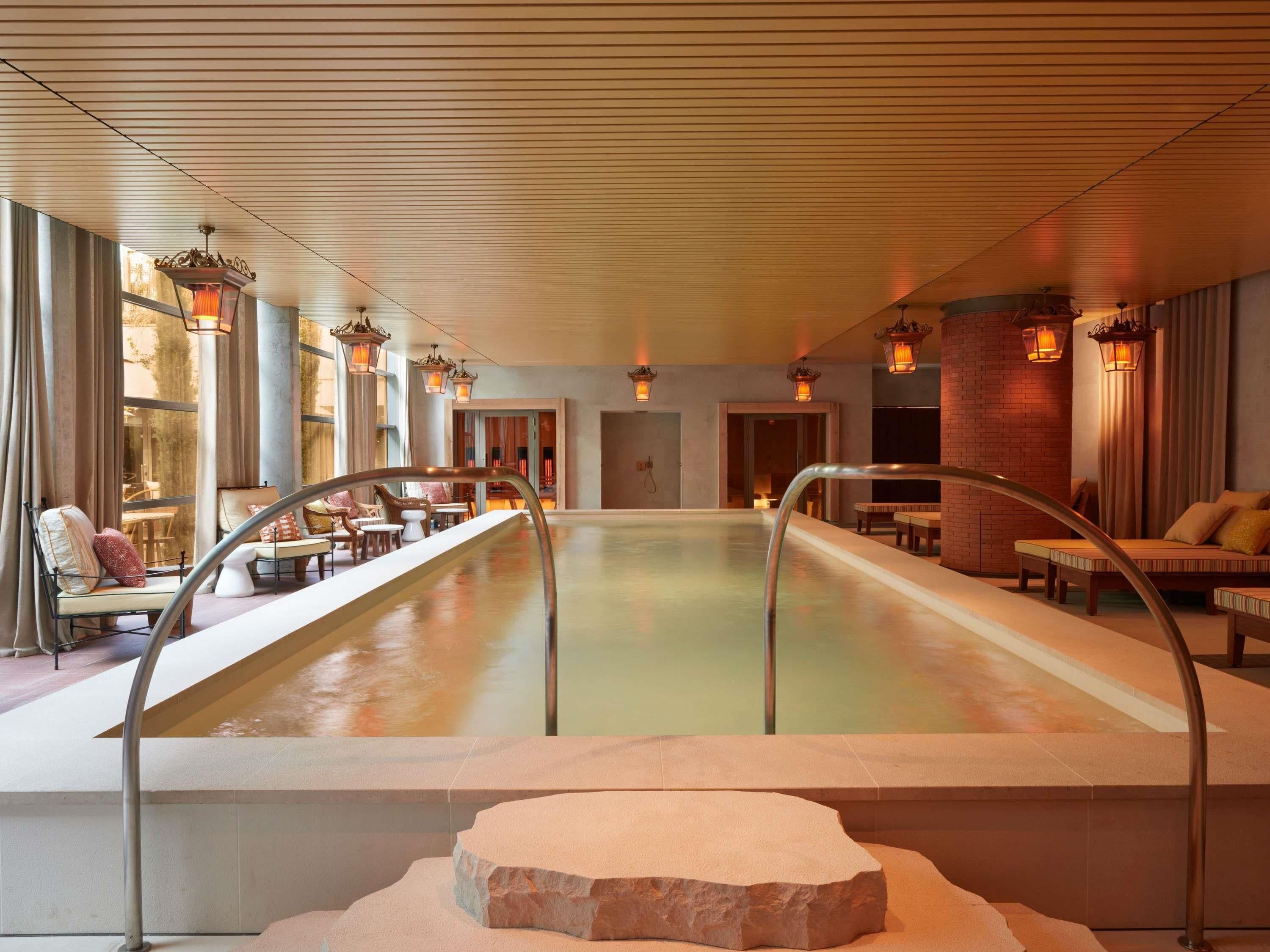 Uma área de spa com uma piscina grande, espaços para relaxar e iluminação ambiente.