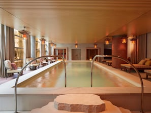 Ein Wellnessbereich mit großem Pool, Sitzbereichen und stimmungsvoller Beleuchtung.