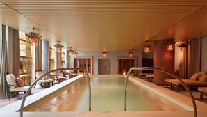 Un área de spa con una piscina grande, zonas de estar e iluminación ambiental.