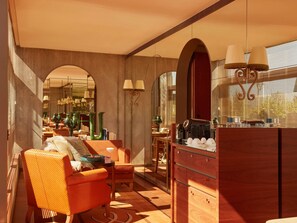 A modern interior with a sofa, coffee table, and a bar area with a coffee machine.