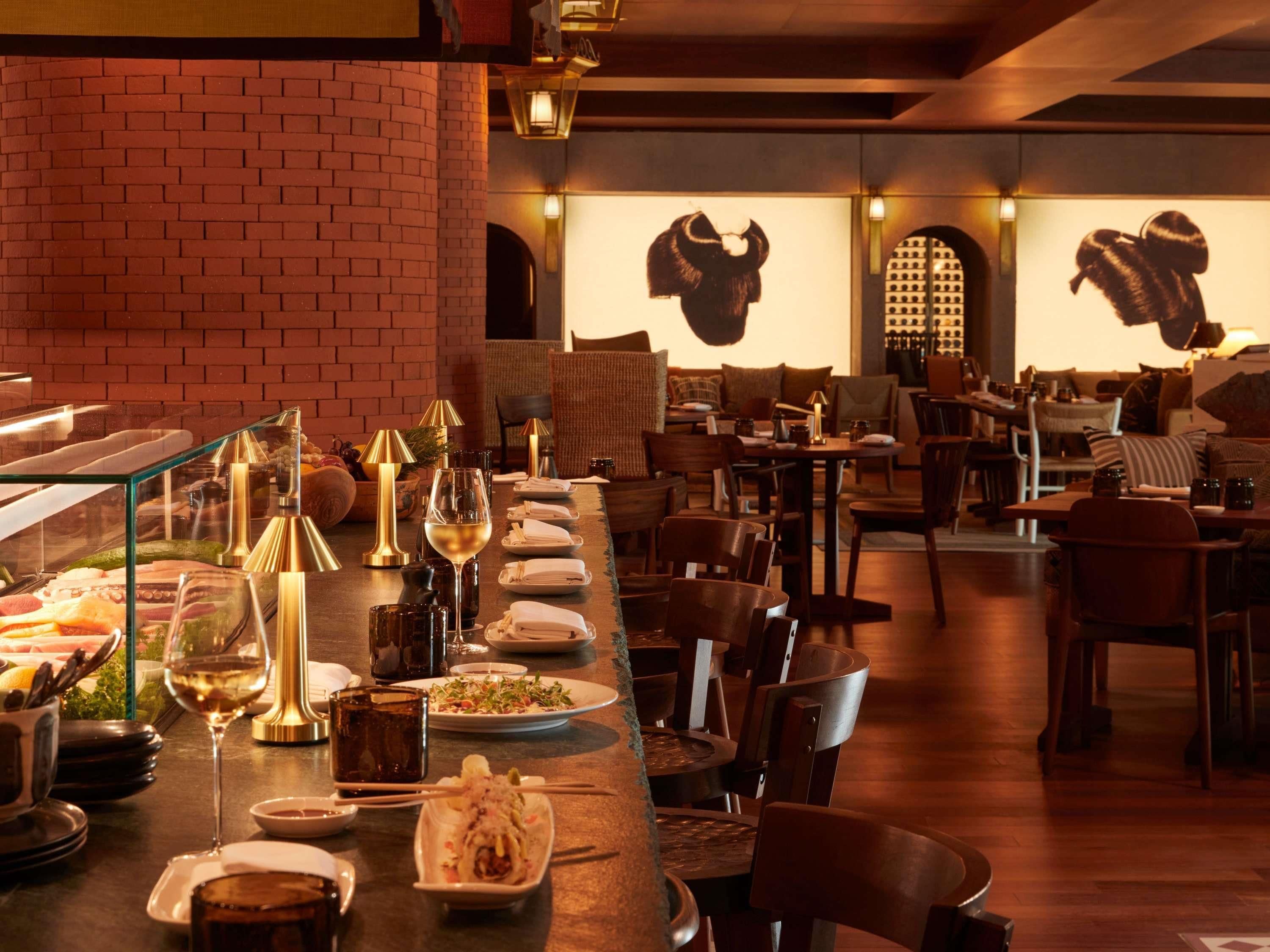 A restaurant with a long counter, various dishes, and wine glasses.