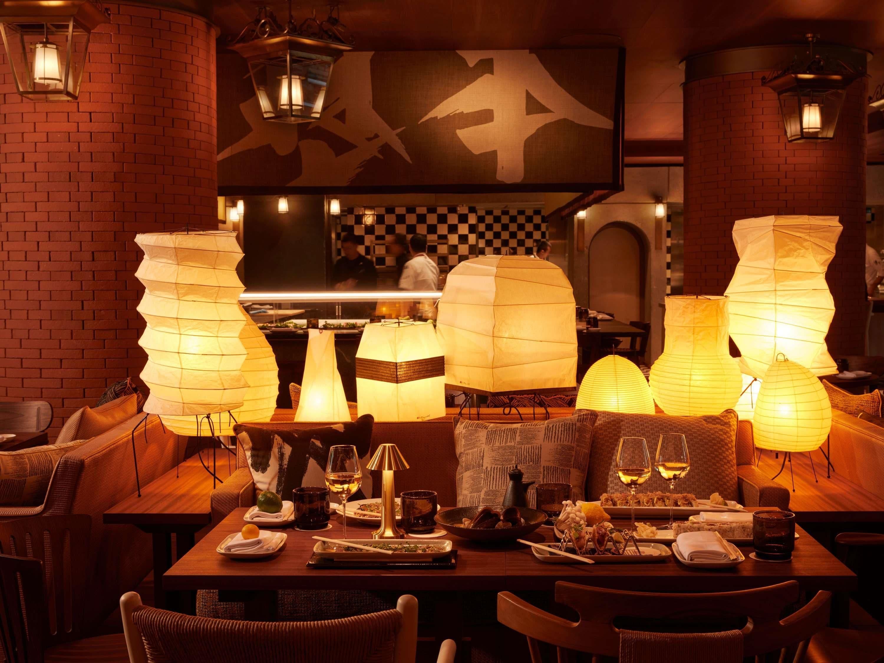 A restaurant with brick walls, hanging paper lanterns, and a checkered pattern on the back wall.