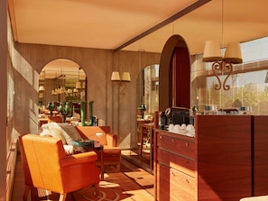 A modern interior with a sofa, coffee table, and a bar area with a coffee machine.
