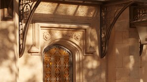 Una entrada de edificio con una puerta de madera grande, un arco de piedra y un toldo de metal.