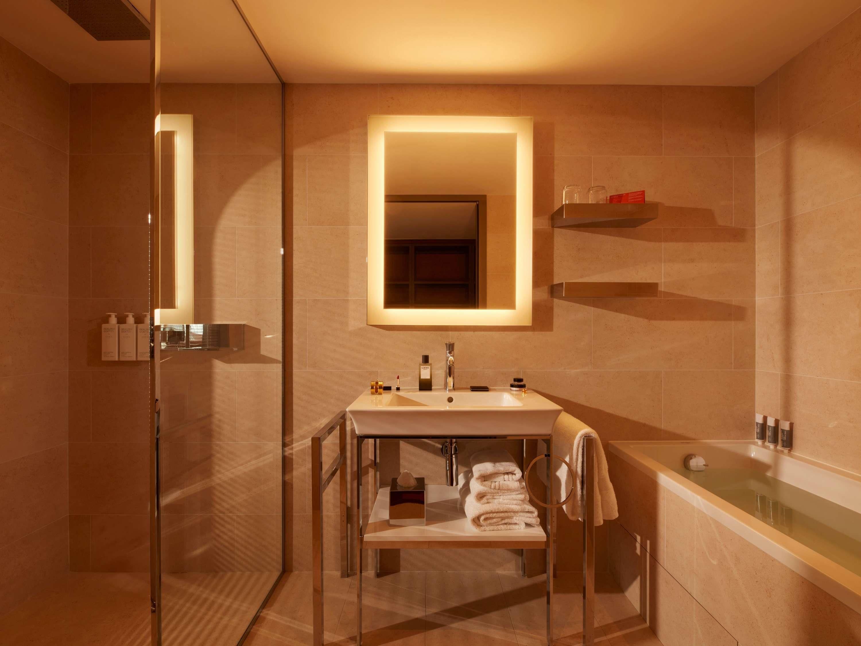 Un baño moderno con cabina de ducha de vidrio, tocador con espejo y bañera.