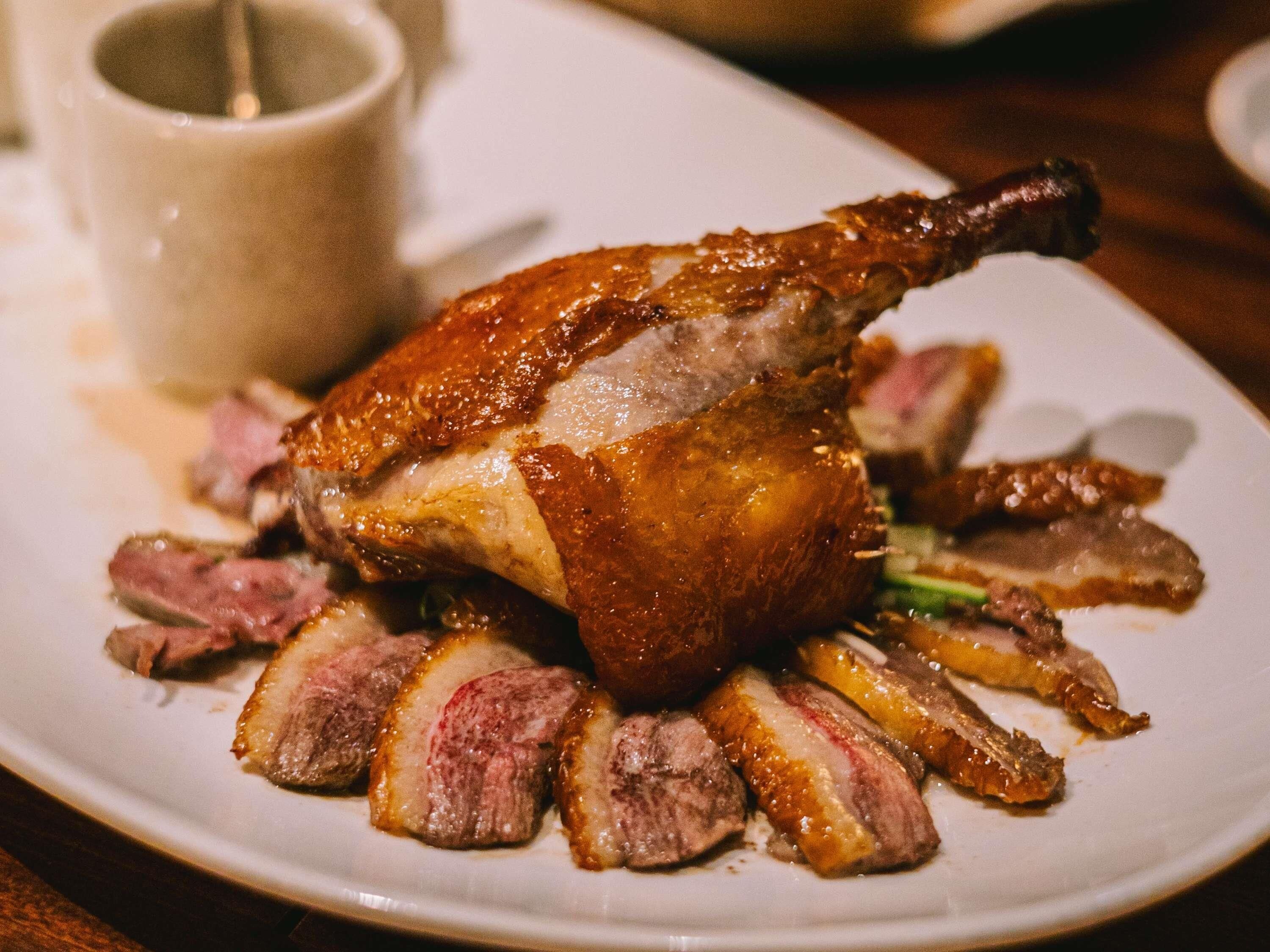 A roasted duck with sliced meat on a plate.