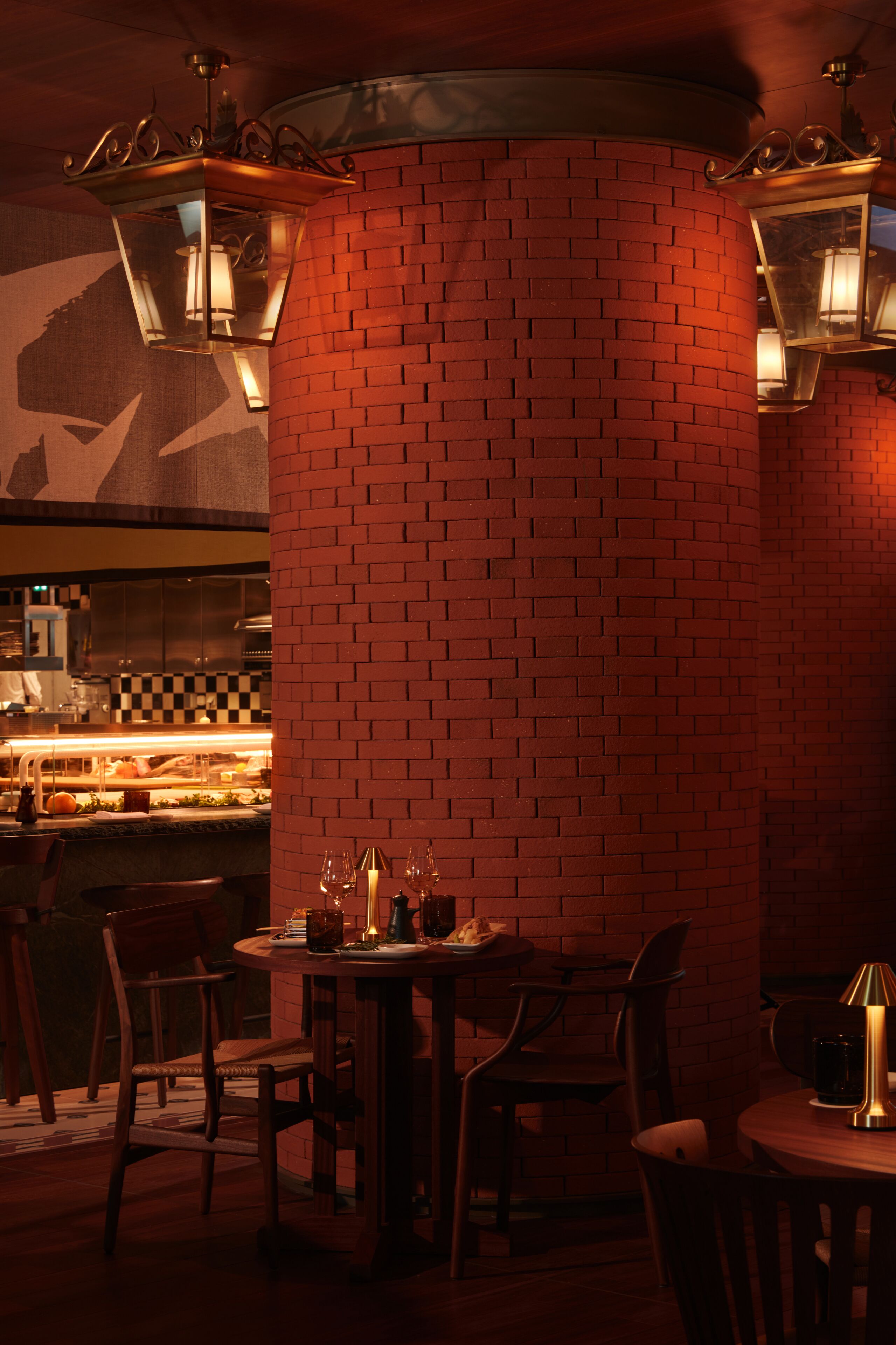 A dimly lit restaurant with brick walls, wooden tables, and chairs.