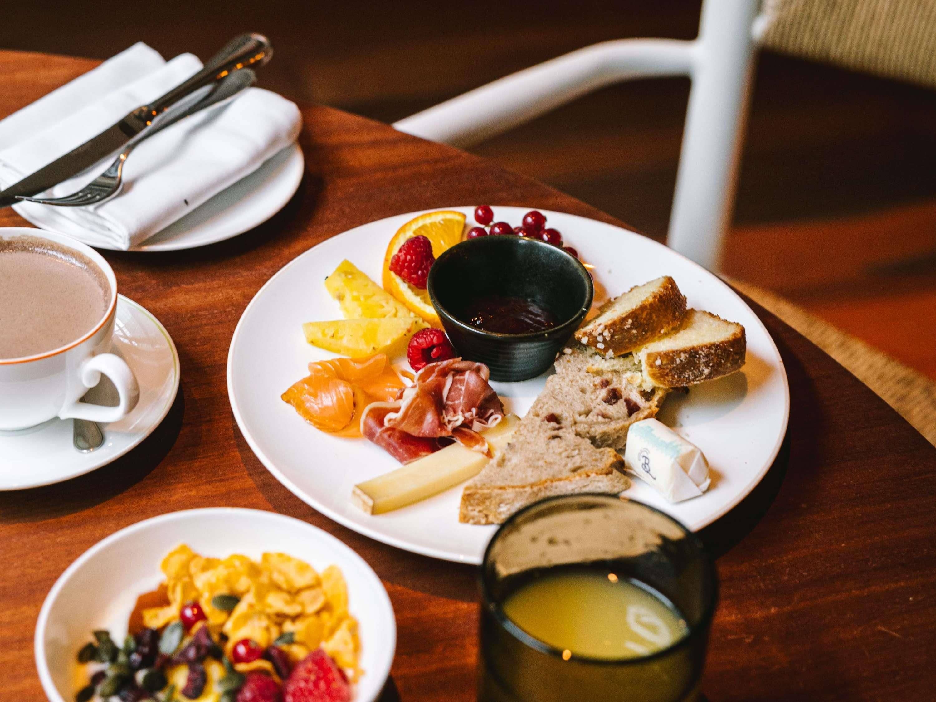 Ein Frühstückstisch mit Toast, Obst und einer Kaffeetasse auf einer Holztischplatte.