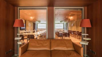 Ein Hotelzimmer mit großem Fenster, einer Couch und einem Tisch mit Lampe.