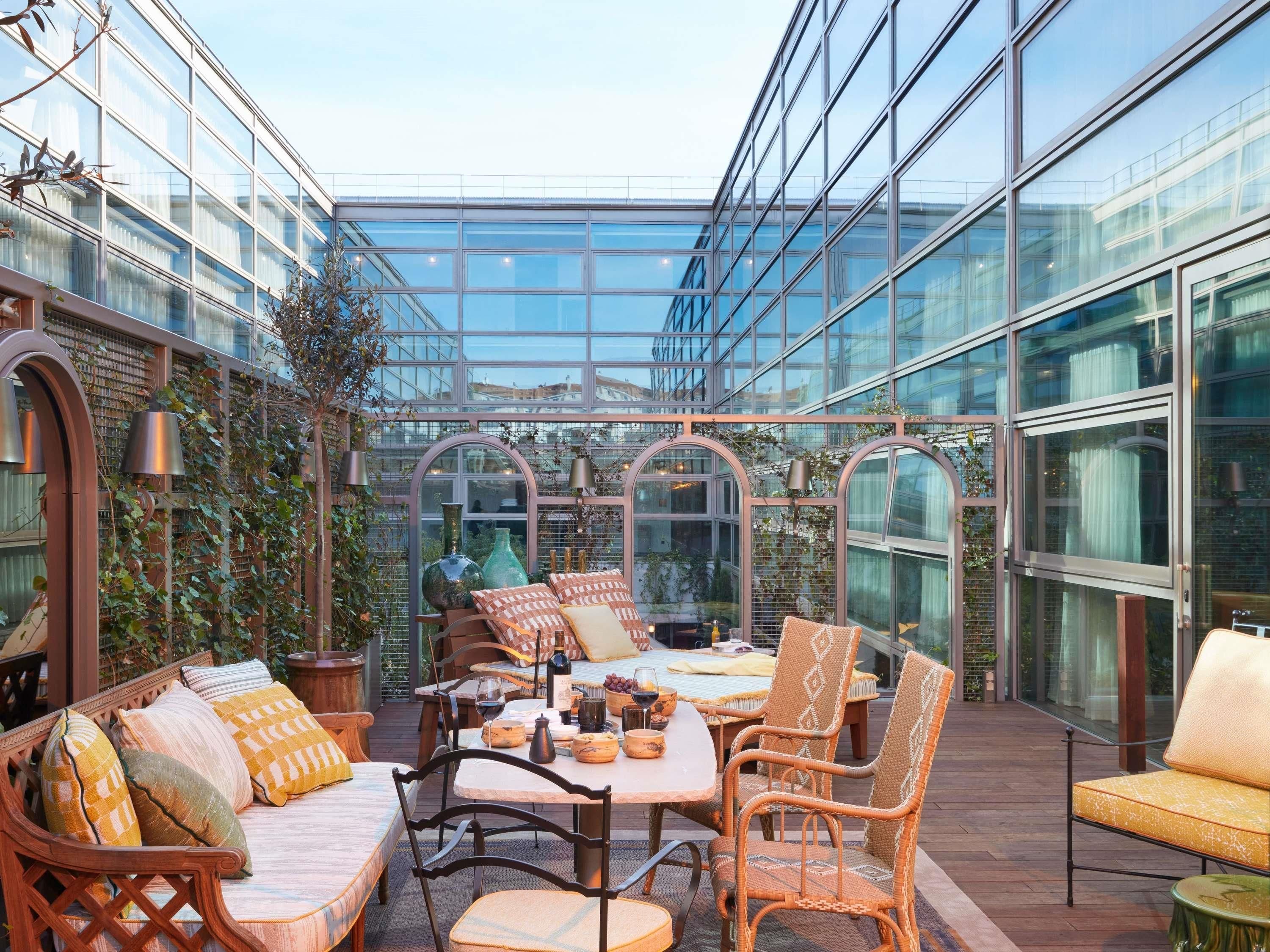 A glass-enclosed patio with seating, a table, and decorative items.