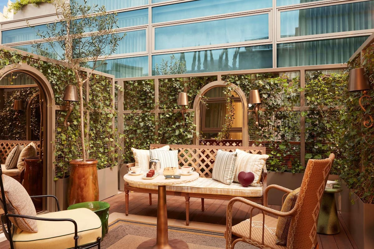 A cozy outdoor seating area with a round table, cushioned chairs, and a bench.