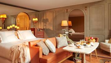Una habitación de hotel con cama, sofá, mesa de comedor y desayuno, y un espejo.