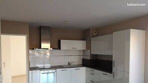Een moderne keuken met witte kasten, een fornuis en een koelkast.
