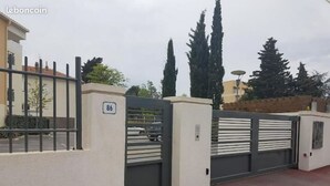 Een hekpoort met een nummer 86 bord, een metalen poort en een gebouw op de achtergrond.