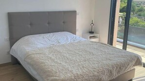Een moderne slaapkamer met een groot bed, een raam en uitzicht op groen.