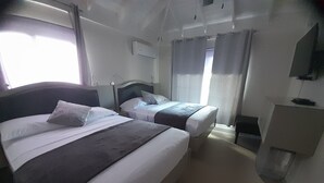 A hotel room with two beds, a desk, a chair, and a television on the wall. - Near Dunn's River Falls, w/Pool, Beach Access, A/C, WiFi, Playpen & baby bath (Ocho Rios)