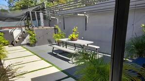 A patio area with a table and benches, surrounded by potted plants and a decorative sign. - Near Dunn's River Falls, w/Pool, Beach Access, A/C, WiFi, Playpen & baby bath (Ocho Rios)